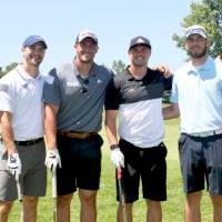 group of 4 football alumni on the green with their clubs